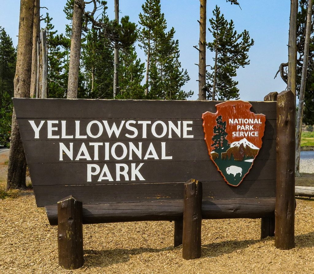 The iconic wooden sign for Yellowstone National Park with its distinctive shield emblem in Wind River Country.