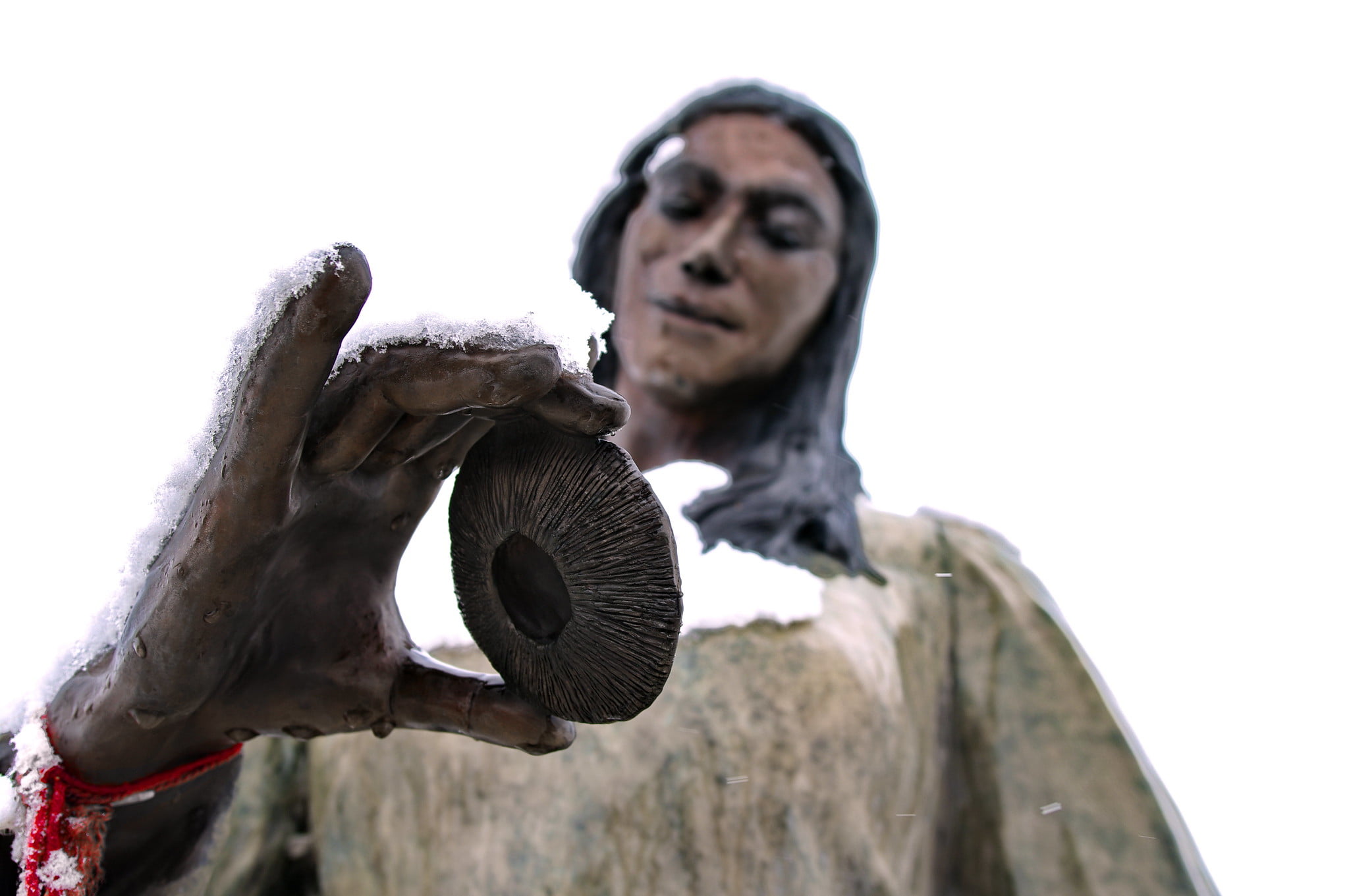 A statue of a woman with long hair holds a snow-covered circular object in her hand in Wind River Country.