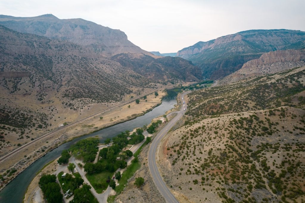 Aerial view of a winding river surrounded by rugged mountains and desert landscapes in Wind River Country.
