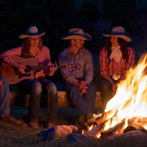 A group of guest ranch guests gather around a campfire for songs and stories.