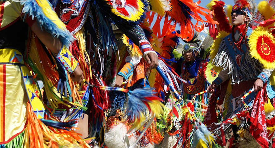 Colorful Native American dancers in vibrant traditional costumes perform at a powwow in Wind River Country.