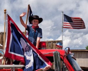Little boy on an old fire truck with Wyoming and American flag in Dubois, WY