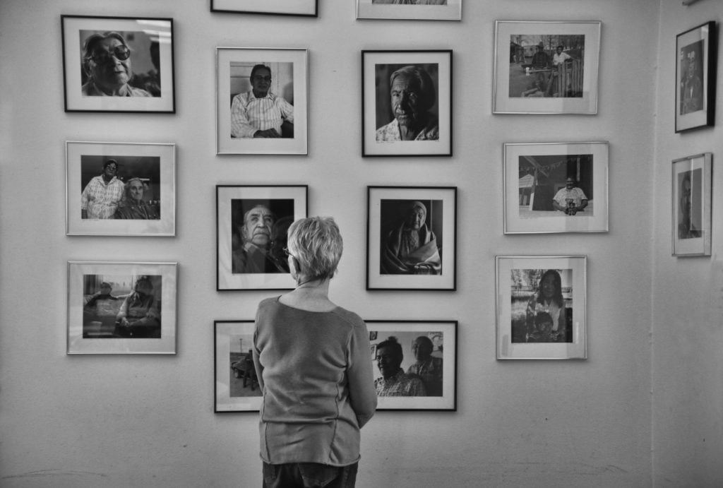 Sara Wiles looking at a wall of her photographs