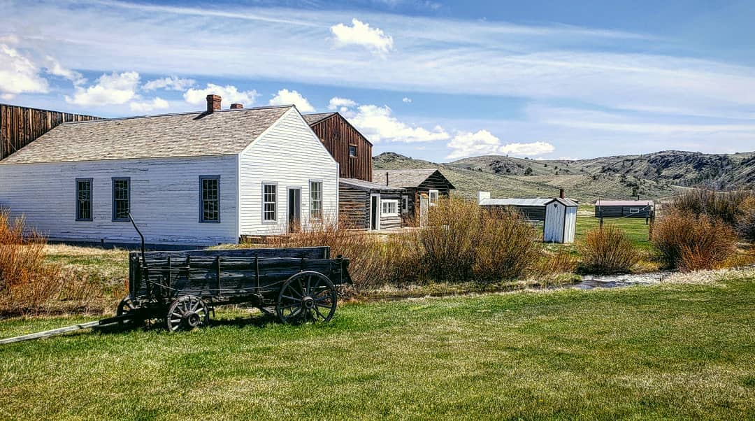A wagon parked in front of a white house in the South Pass City Historic Site, a former gold mining town in Wyoming.