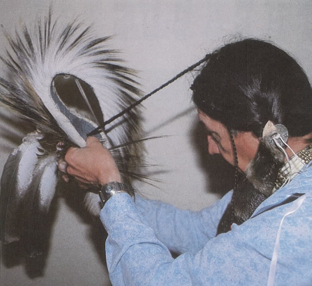 A person adjusting a traditional Native American porcupine quill roach headdress in Wind River Country.