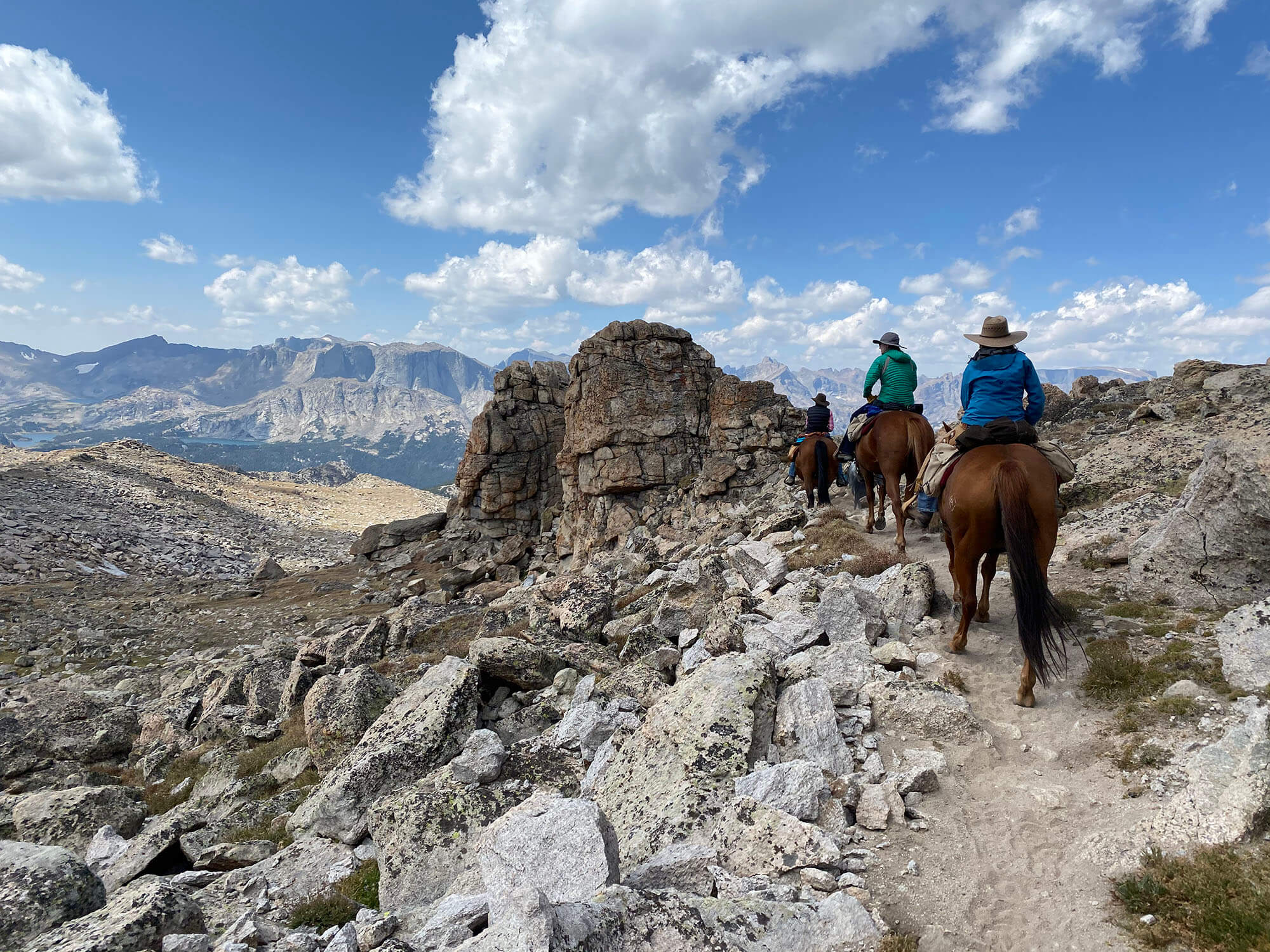 Horseback riding through rocky terrain in Wyoming, with wide open spaces and clear skies. Credit: Paula McCormick.