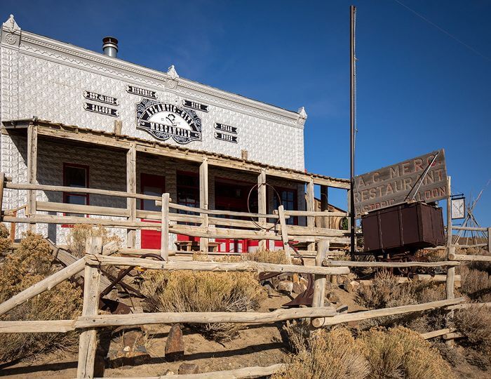 An old western-style building with a sign for 'A.C. Mer's Restaurant' and a rustic wooden fence in Wind River Country.
