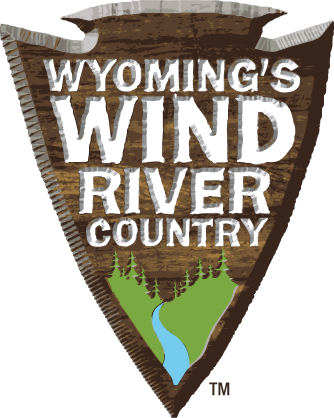 A wooden sign with the text 'Wyoming's Wind River Country' and a green mountain landscape with a river and trees in Wind River Country.