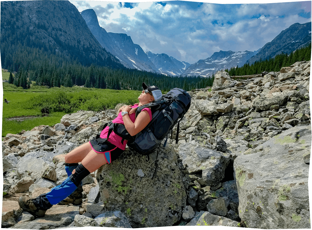 A backpacker leaning on a rock.