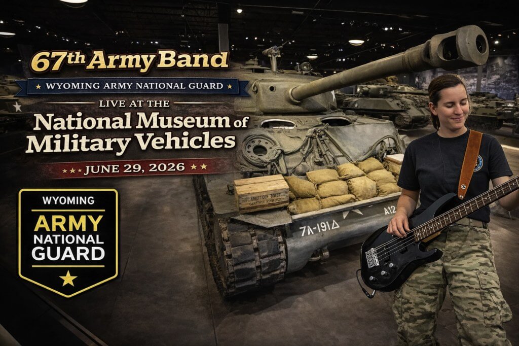 A musician in military camouflage plays an electric bass guitar in front of a vintage tank at the National Museum of Military Vehicles in Wind River Country.