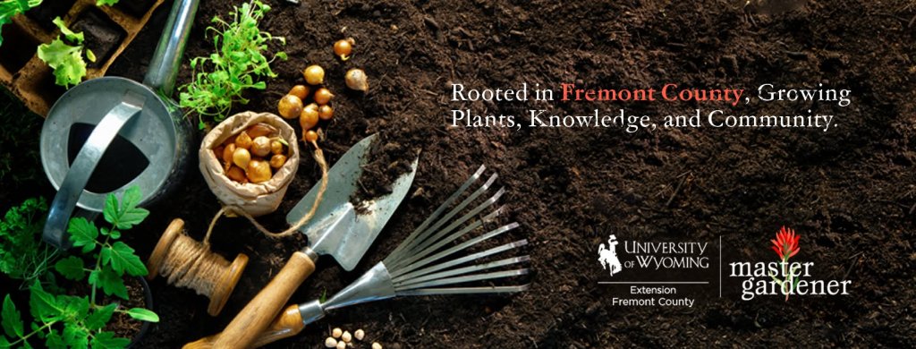 Gardening tools, seedlings, and bulbs arranged on dark soil with University of Wyoming branding in Wind River Country.